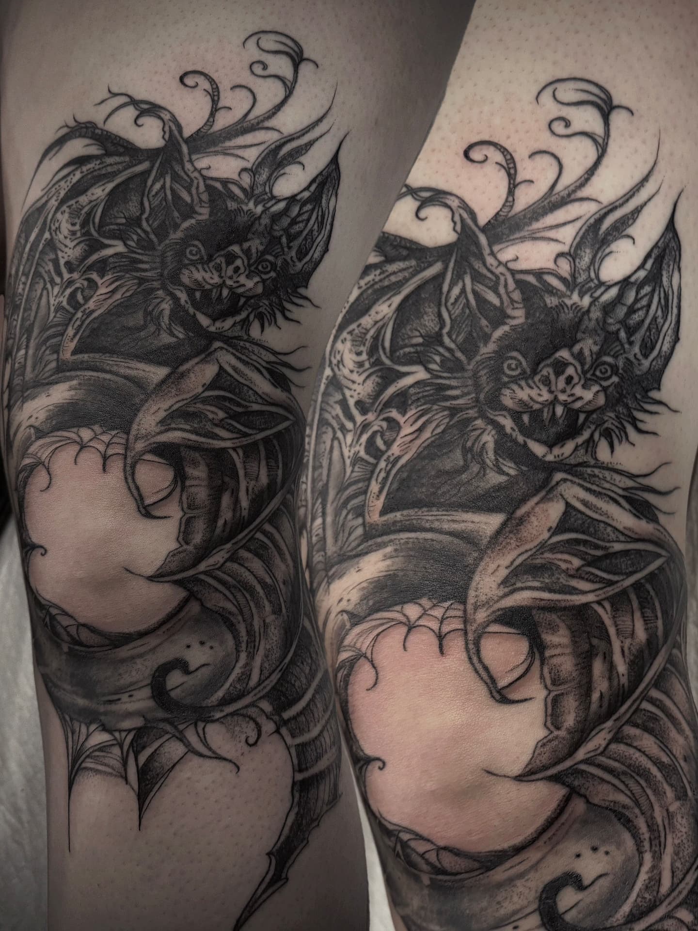 Winged bat-cat knee piece with webbing and curling smoke, shown from two angles