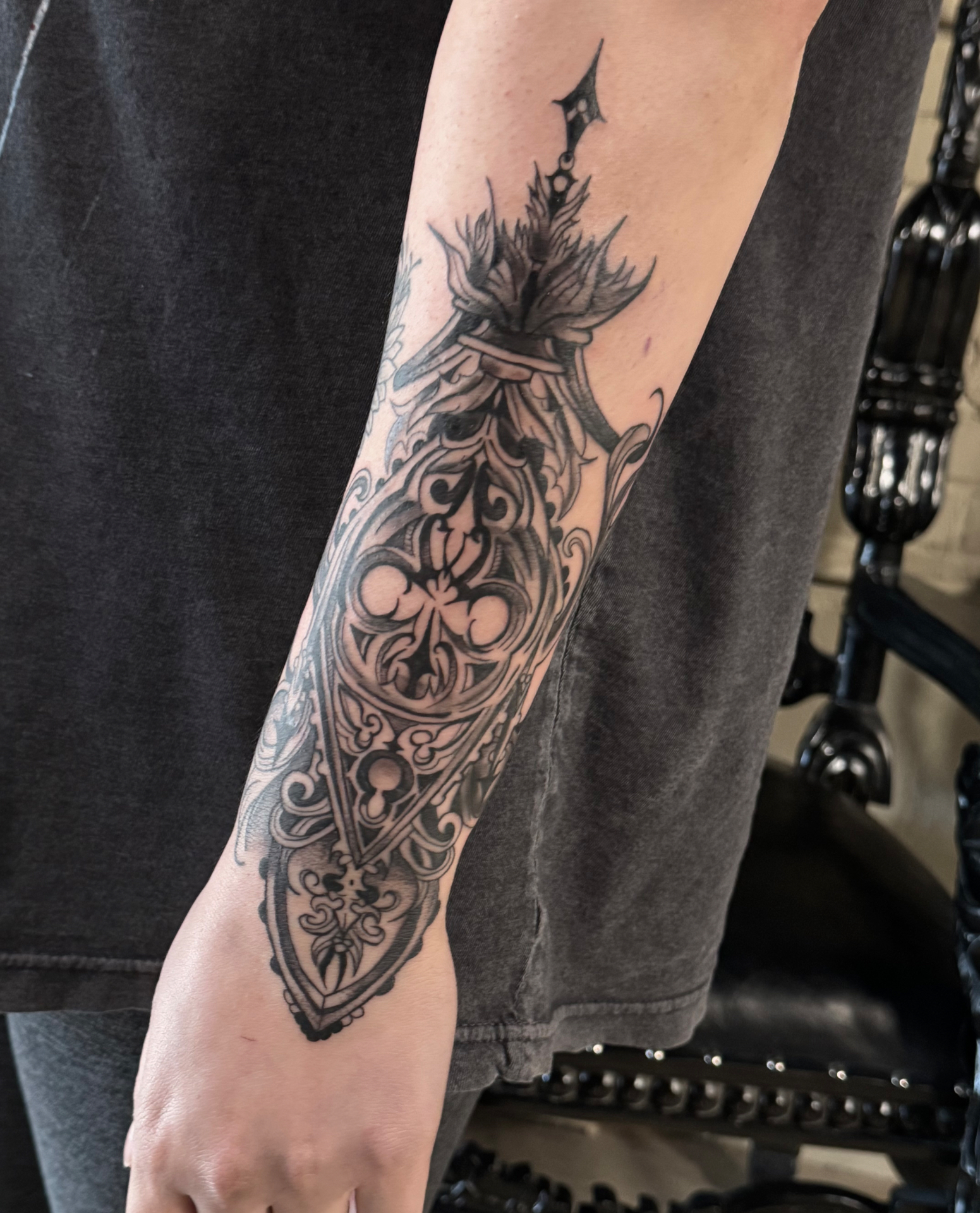 A gothic reliquary forearm piece with quatrefoil tracery, filigree scrolls and a flaming finial.