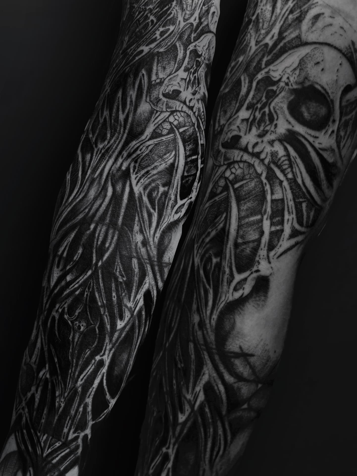 Dark blackwork sleeves with skulls and flowing organic linework